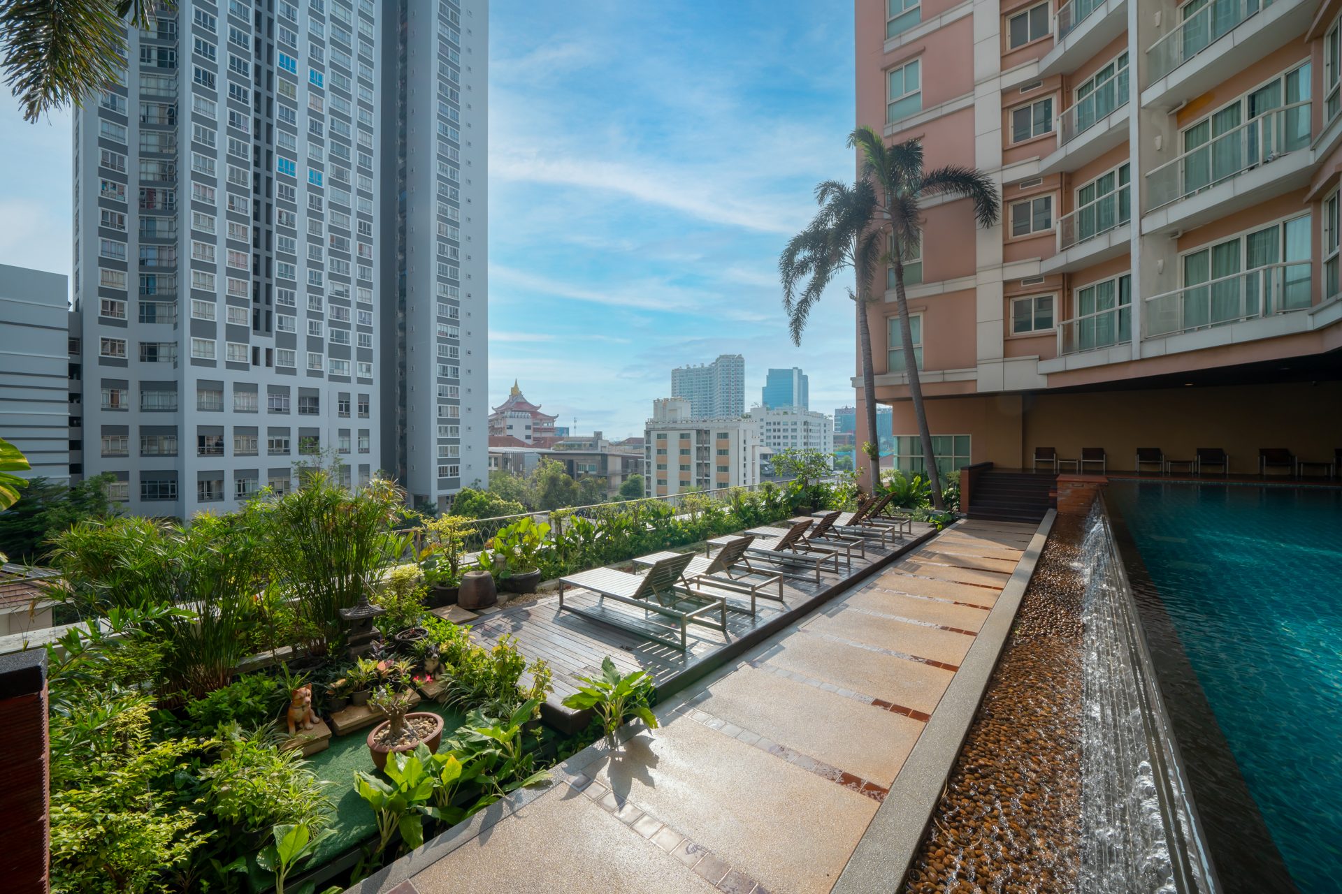 Rooftop pool deck with sun loungers and Bangkok skyline